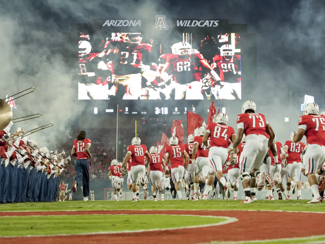 Image of Arizona football team running onto the field at a UA home game