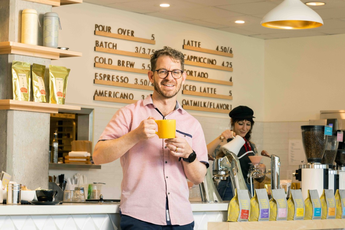 Man holds mug at cafe counter