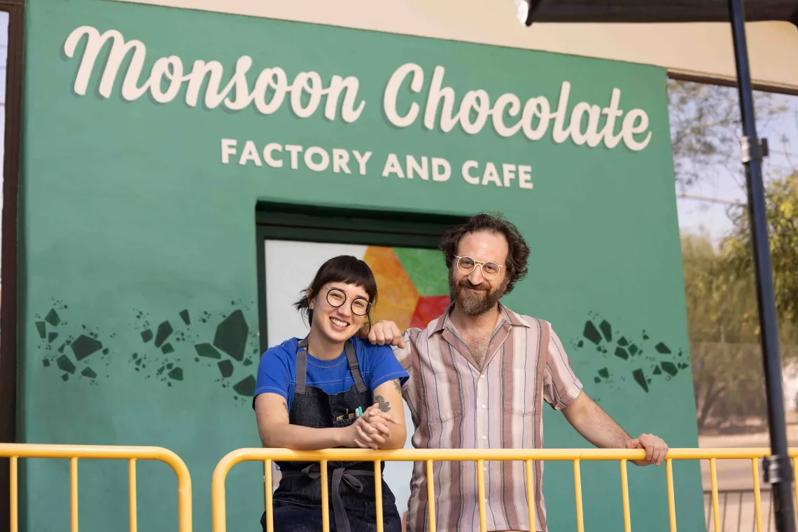 A man and woman pose in front of a storefront 