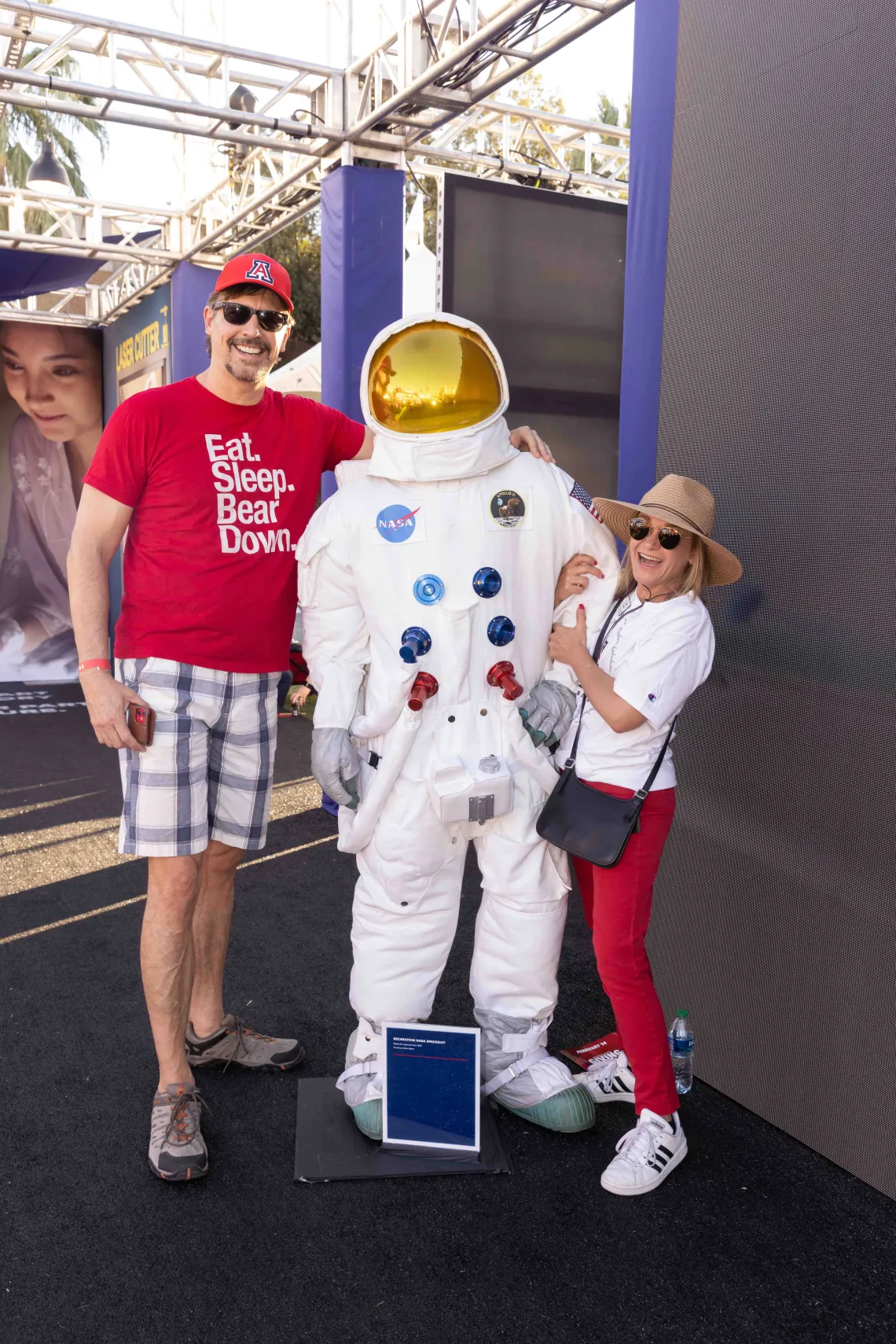 Two individuals post next to spacesuit