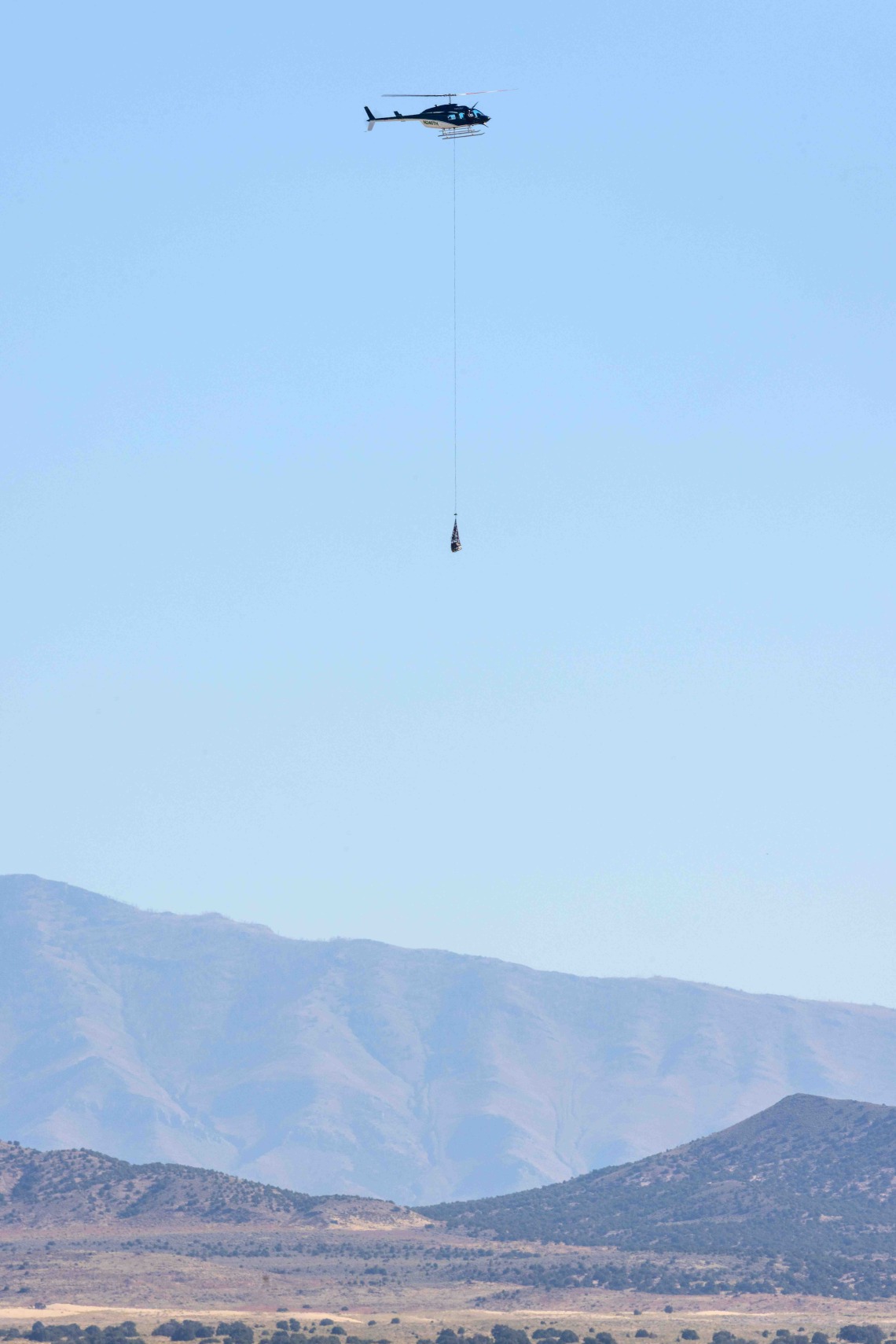 A helicopter transports the  sample return capsule to a  cleanroom after its landing in  the Utah desert. 