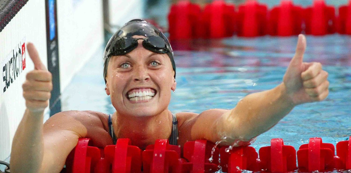 Woman grins in swimming gear with thumbs up gesture