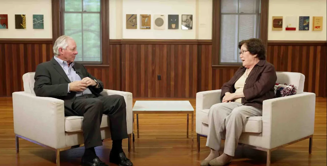 Two professionals engaged in discussion while sitting in white chairs