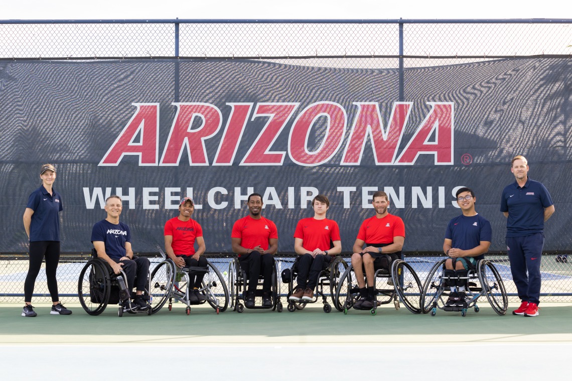 A photograph of six individuals in wheelchairs and two others standing representing the wheelchair tennis program