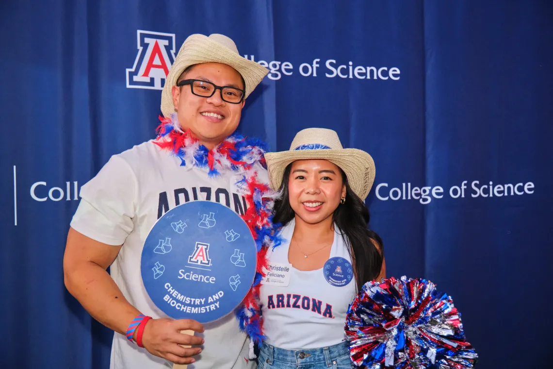 Two college of science students smiling, wearing U of A gear