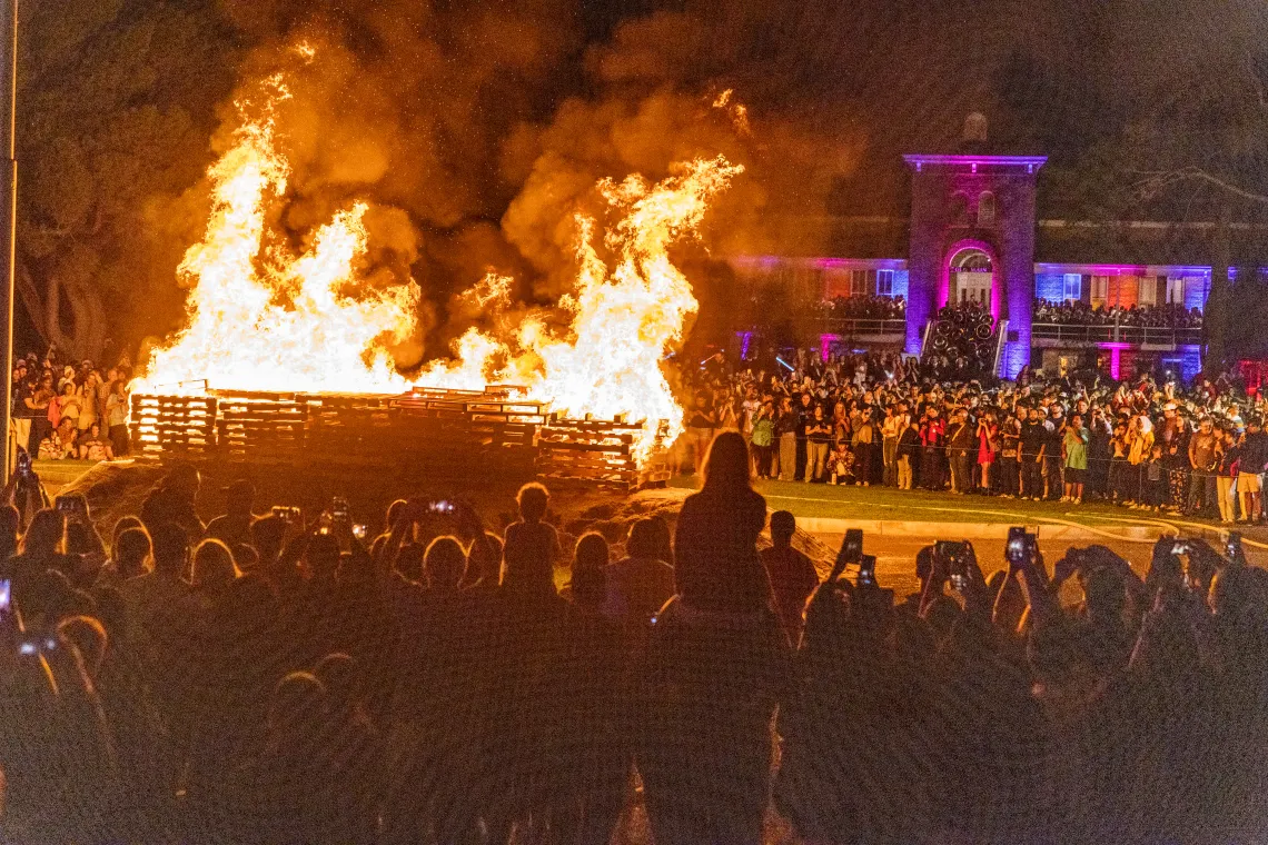 A bonfire in front of Old Main with students surrounding it