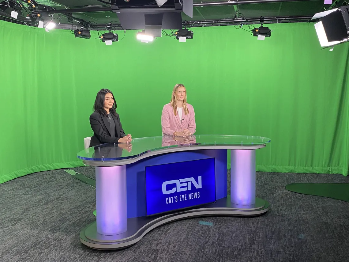 Two journalism students sitting at the news desk