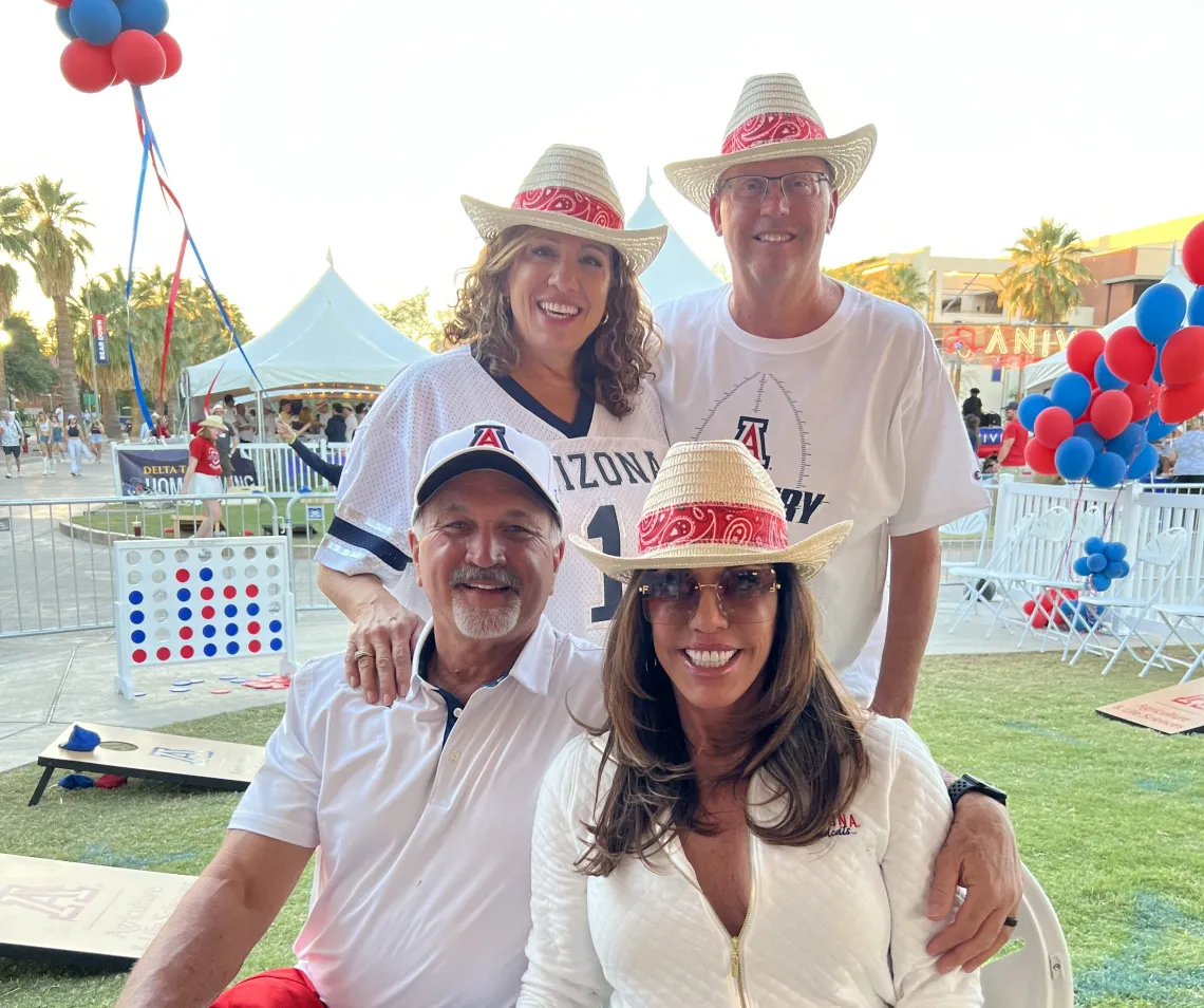 Four Wildcats wearing U of A gear at the homecoming tailgate tent