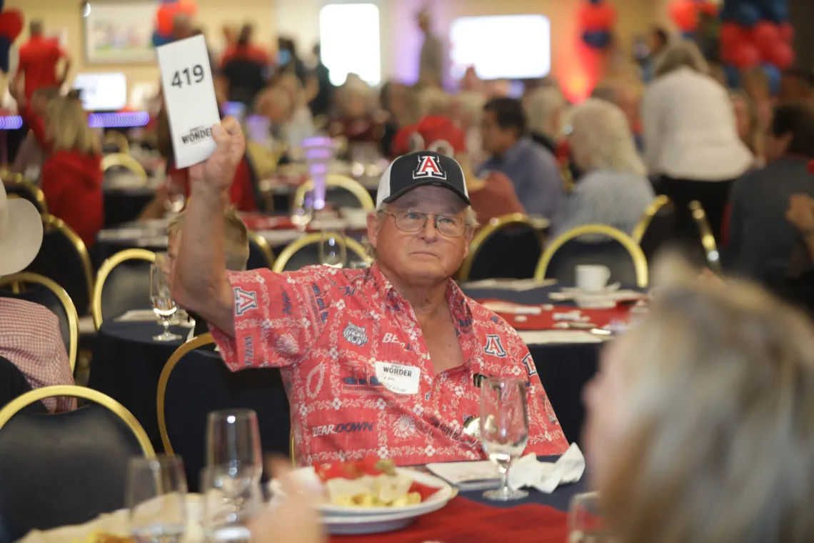 A man holding up a sign with a number on it at a live auction