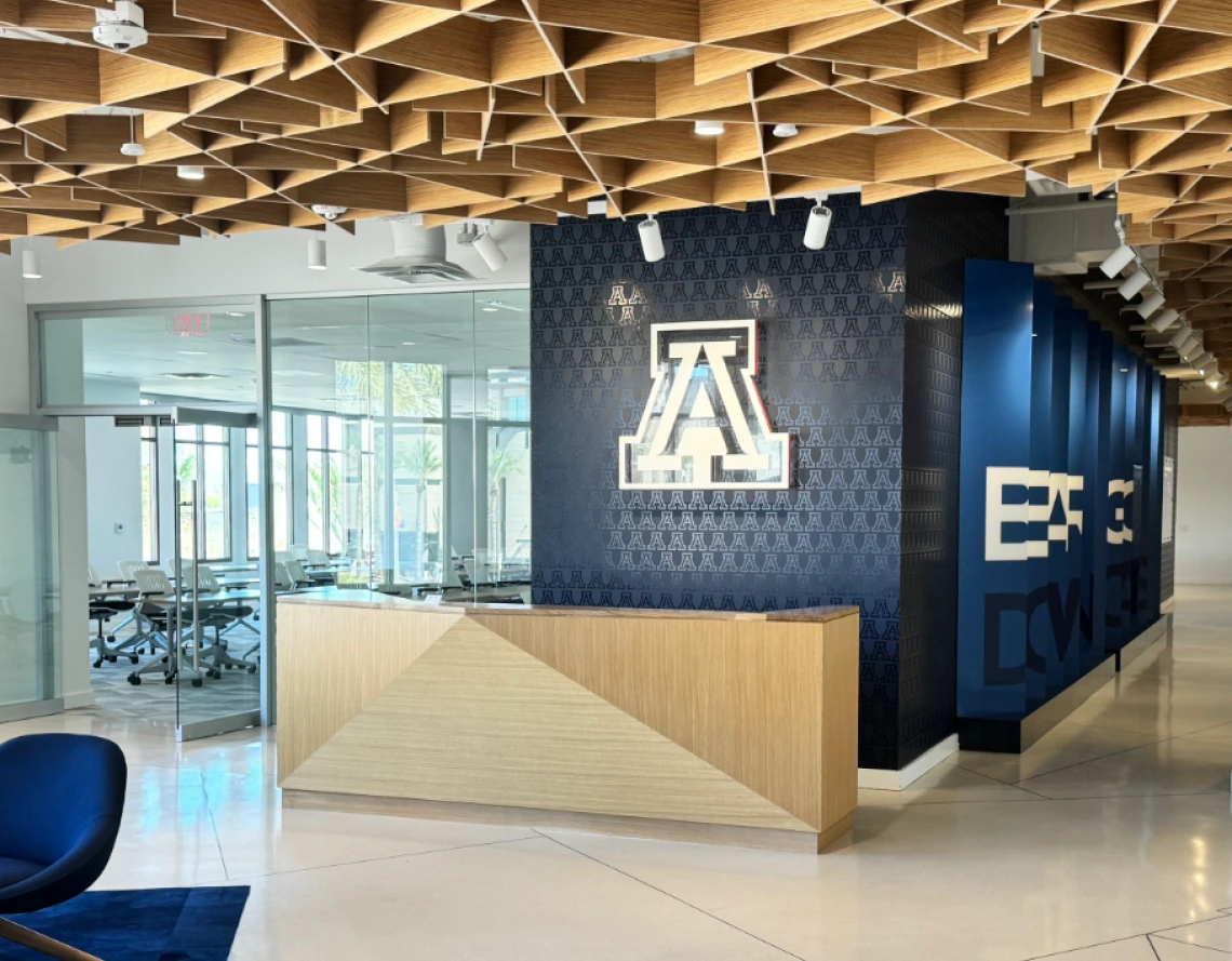 A tan desk with a blue block A decal on the wall behind it, in front of an office space at the U of A Scottsdale Center