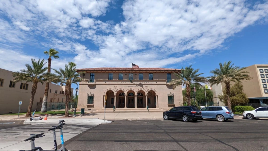 A tan stone building with cars parked on the outside