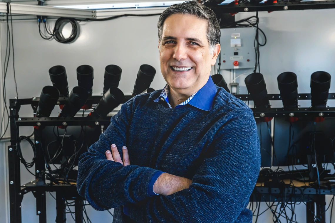 An image of Roberto Furfaro smiling at the camera with his arms crossed. He is in a dark green sweater.