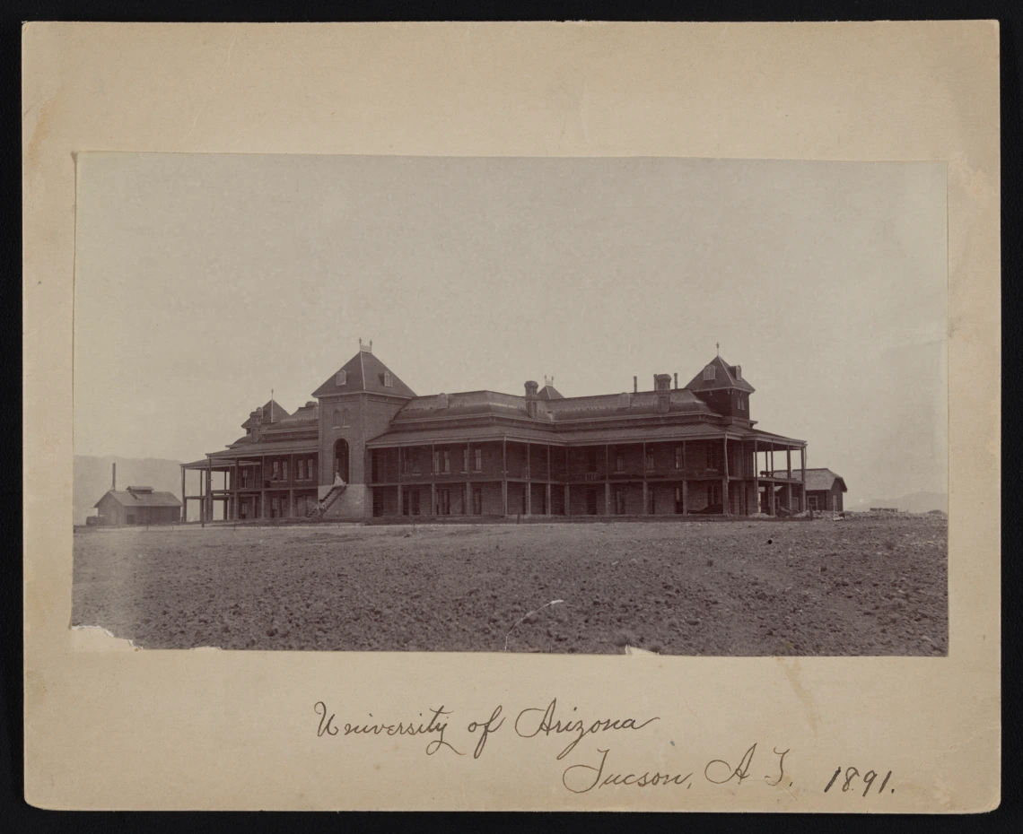 A photograph of Old Main, surrounded by an arid environment, with the words "University of Arizona Tucson, AZ 1891" written in cursive at the bottom. 
