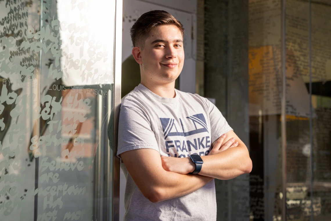A photo of Tadeusz Borowski with his arms crossed, outside the Árbol de la Vida dorm, where he is a resident assistant