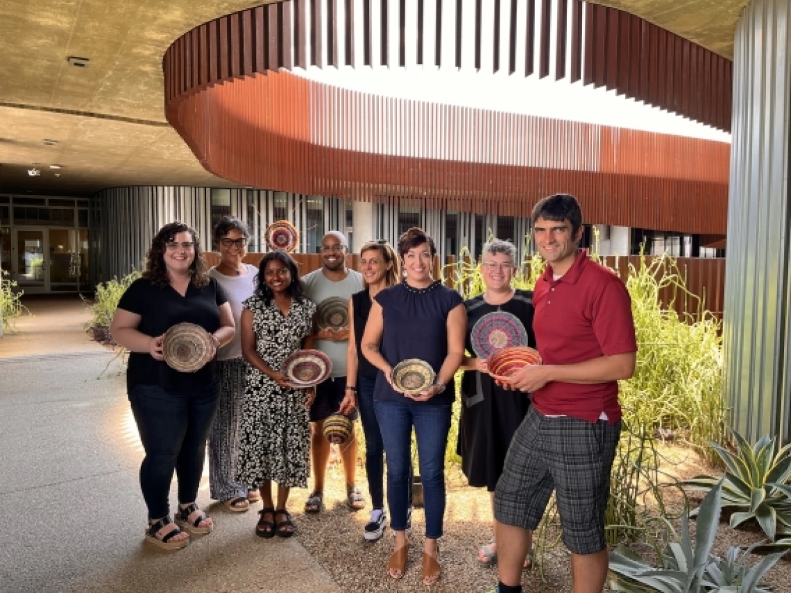 A group of eight people holding woven baskets