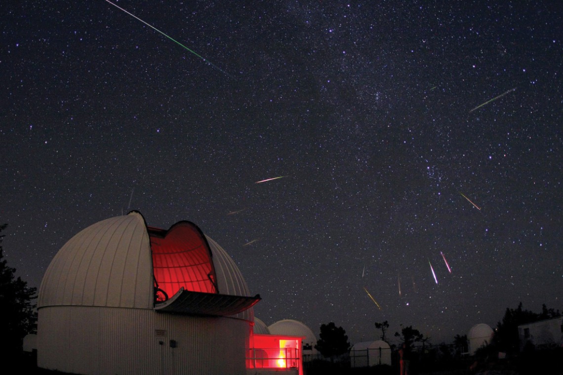 A photograph of the UA Mount Lemmon SkyCenter, surrounded by shooting stars in the background