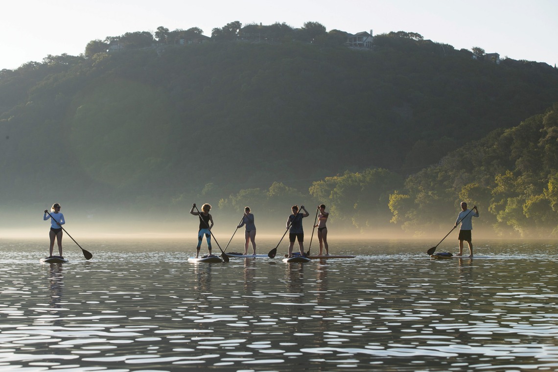A photograph of six individuals paddleboarding in a foggy area