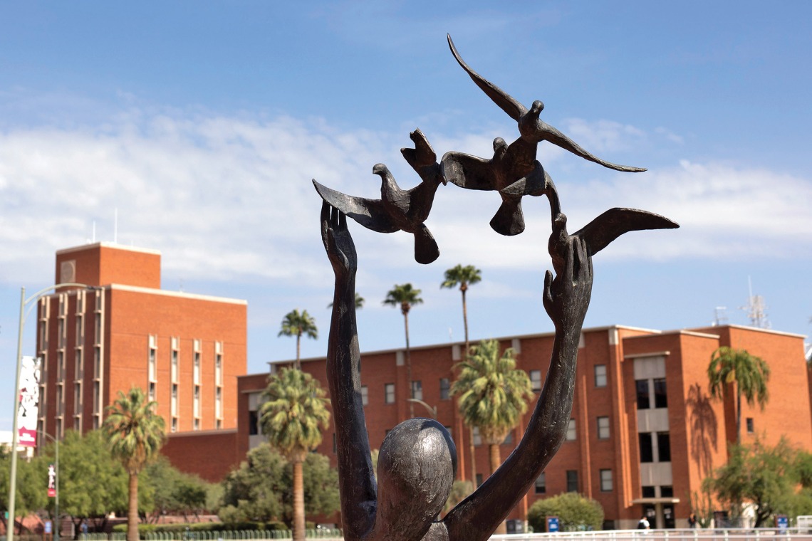 A photograph of the bronze statue of a woman with birds, located in the front of the main library