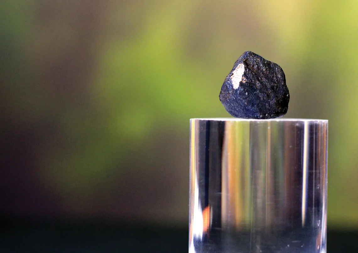 A photograph of a meteorite on a silver stand