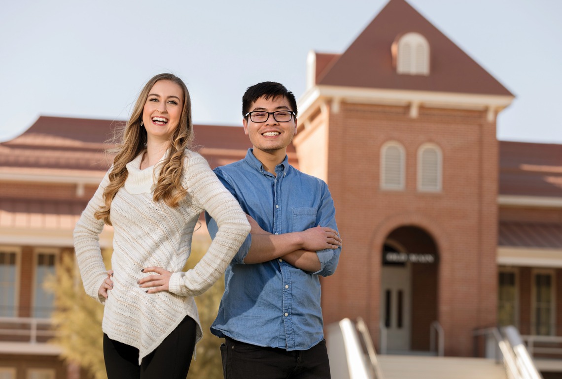 A photograph of Kethia Kong and Morgan Larson smiling and posing in front of Old Main