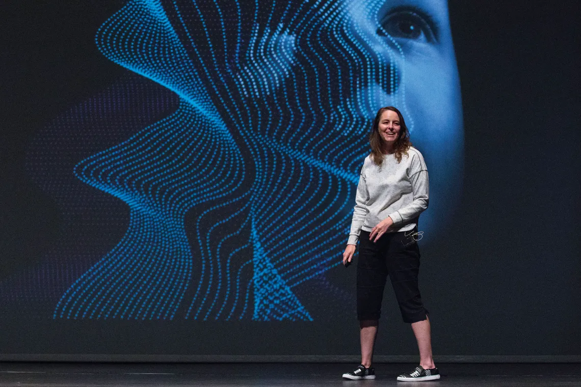 A photograph of Jane Bambauer standing in front of a projection of a child 