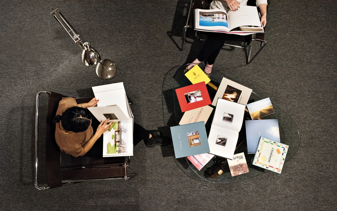 A photograph of two individuals looking through books from a table