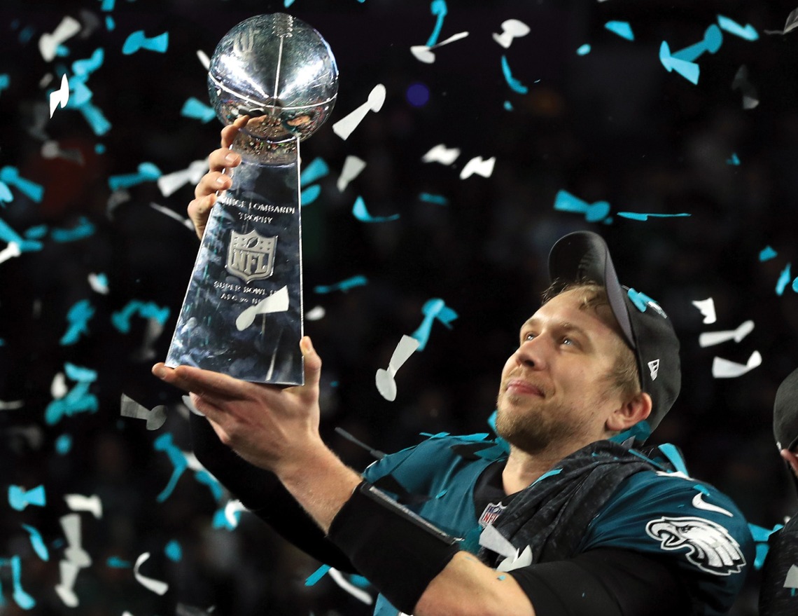 A photograph of Nick Foles holding a trophy and smiling