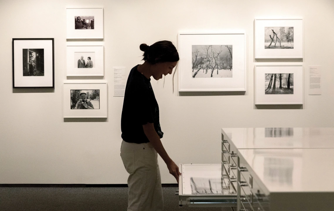 A photograph of a woman looking down at a drawer full of photos