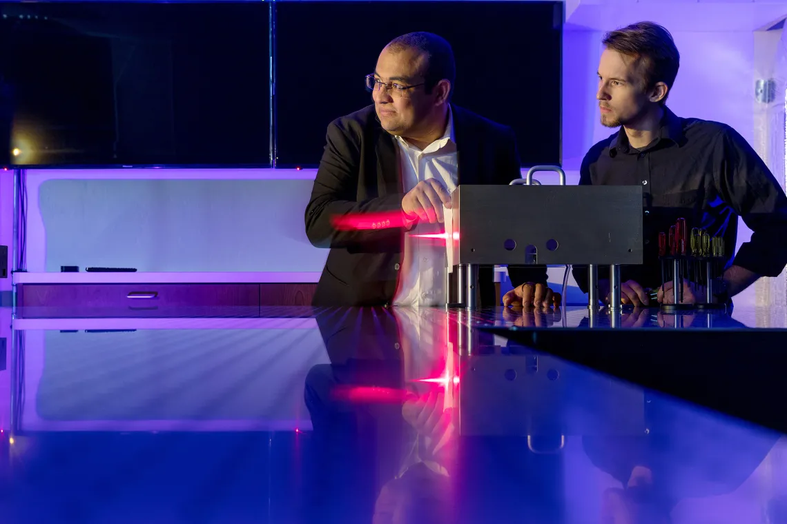 A photograph of Mohammed Hassan and Ian Marsh intensely looking at an attosecond light field synthesizer