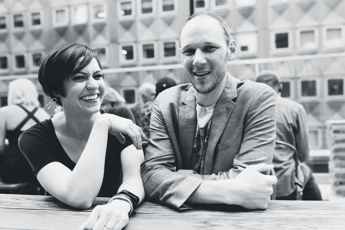 A black and white photograph of Ryan and Sarah Kanto sitting and laughing