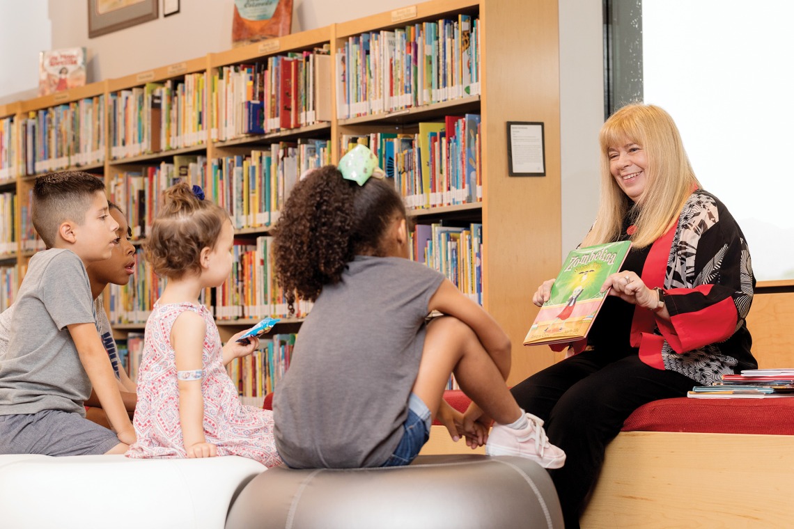 A photograph of Kathy Short reading to three children