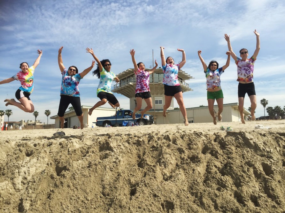 A photograph of students jumping up with excitement at the beach