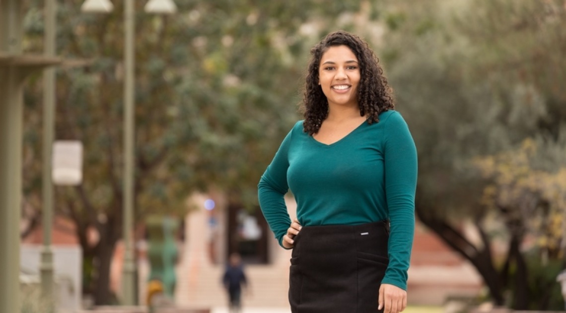 A photograph of Leah Crowder, smiling and posing on the University of Arizona mall 