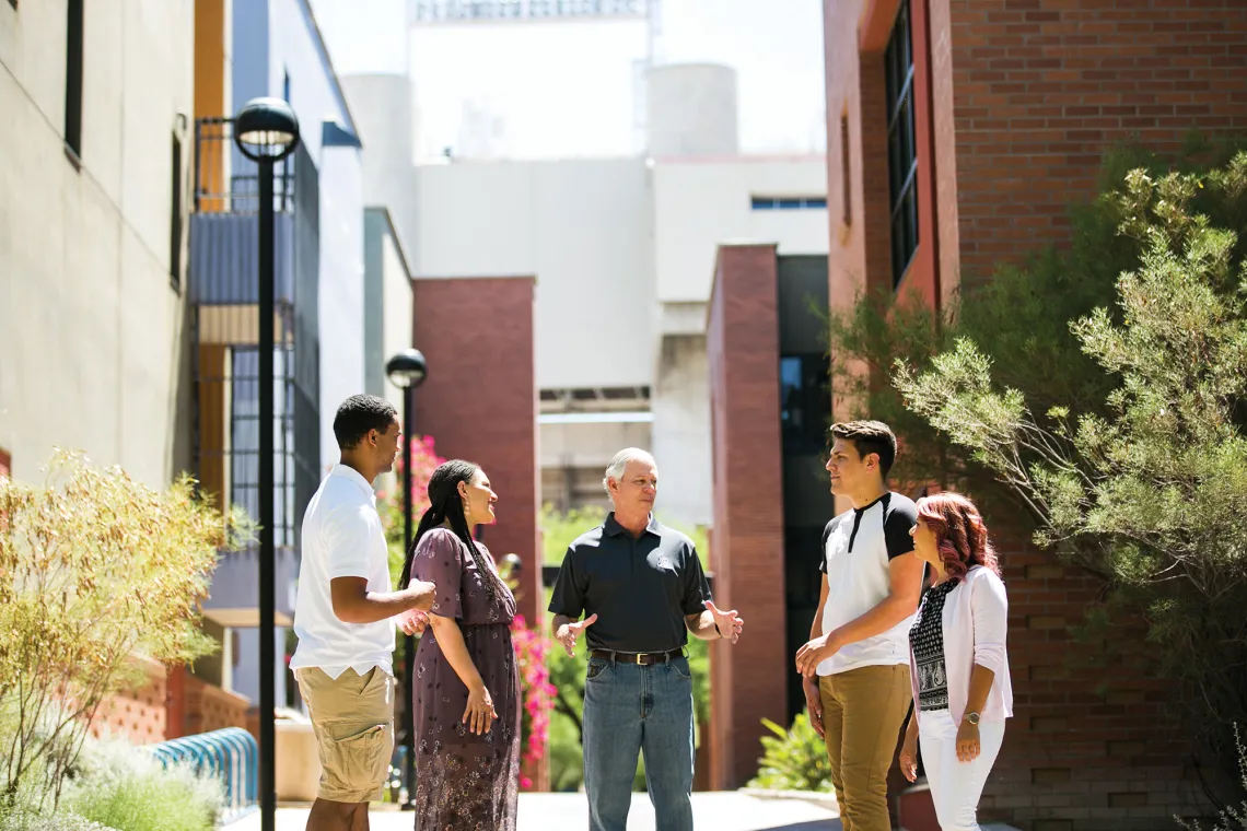 A photograph of Dr. Robert C. Robbins chatting with students and staff on Highland