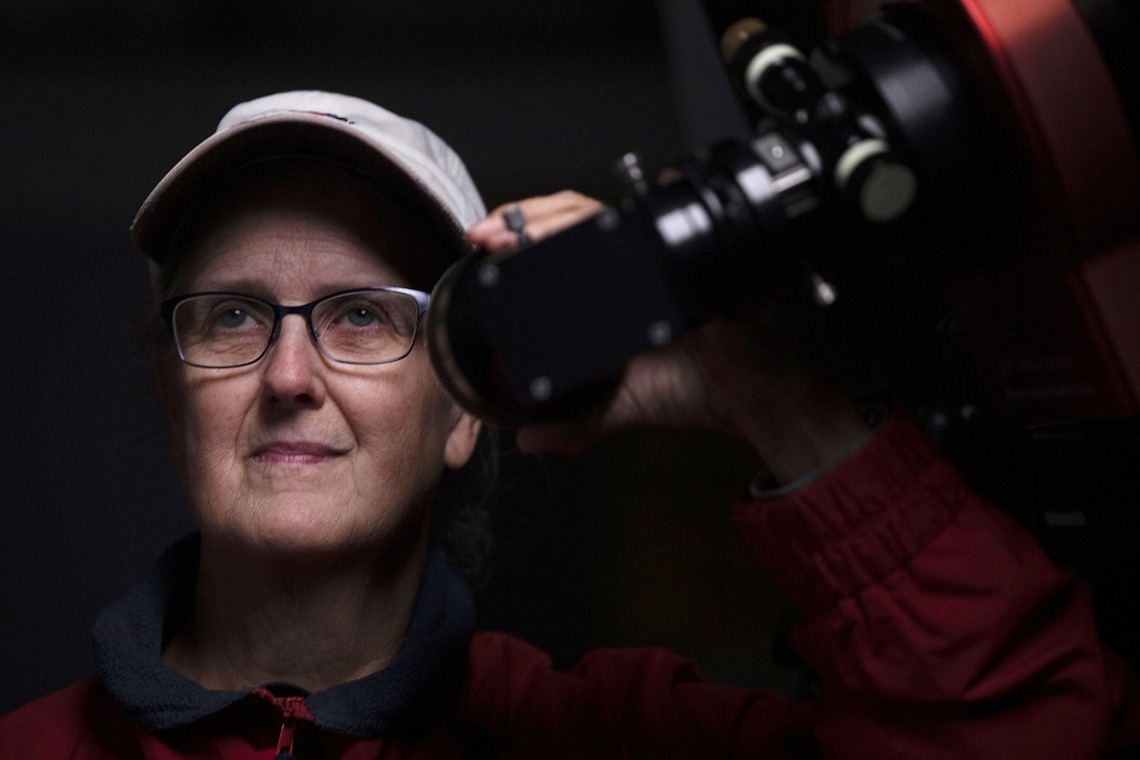 A photograph of Marcia Rieke, the Regents' Professor of Astronomy and associate department head at the University of Arizona, looking through a telescope lens.