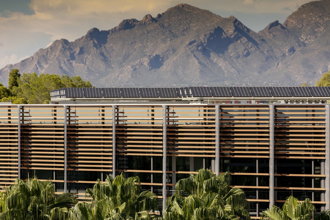 A photograph of solar panels on a building in front of the mountains