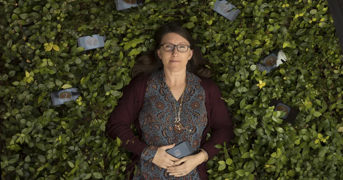 A photograph of Jessica Andrews-Hanna laying down in a bed of leaves 