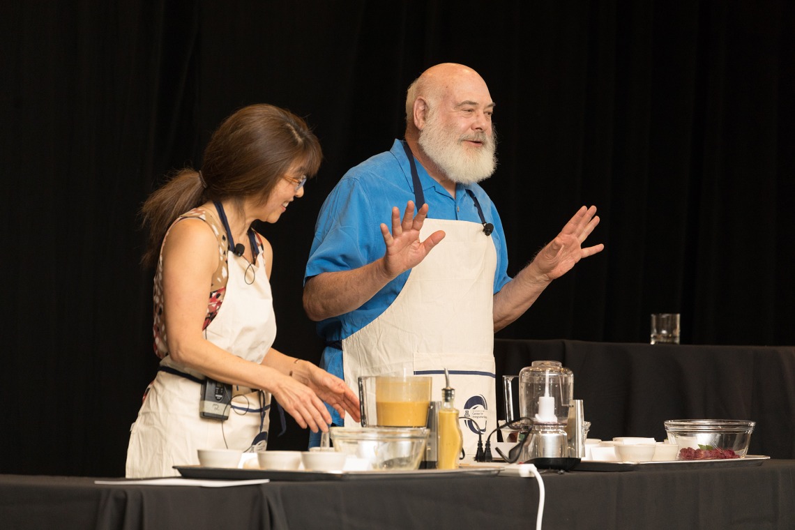 A photograph of Dr. Andrew Weil and a woman demonstrating healthy eating with different ingredients on a table