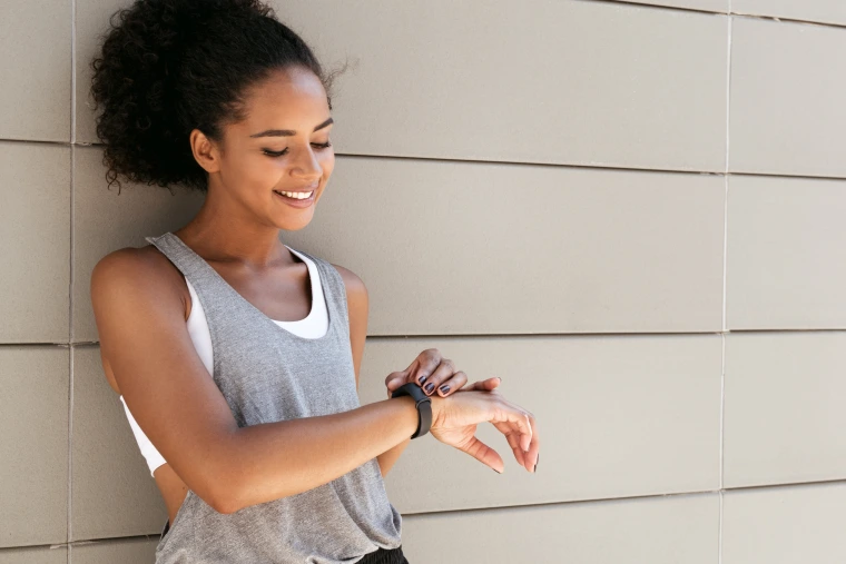 A photograph of a woman adjusting her fitness watch