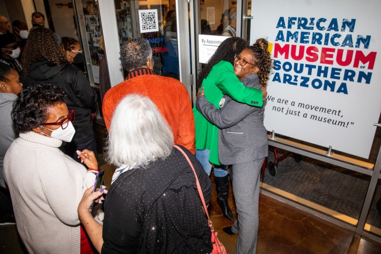 A photograph of individuals celebrating and embracing at African American Museum opening.