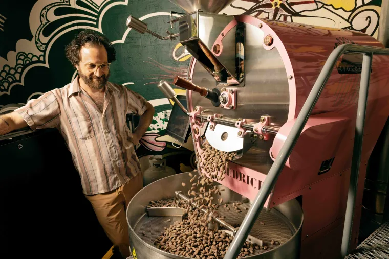 Man poses next to chocolate factory equipment