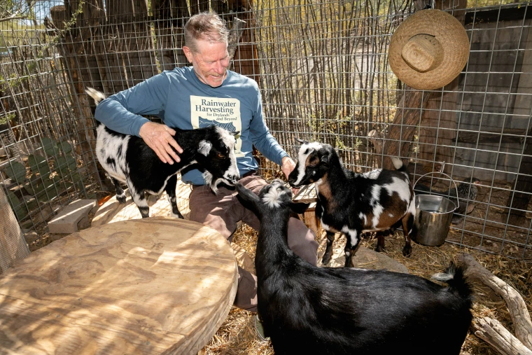 Lancaster feeding his Nigerian Dwarf goats and smiling