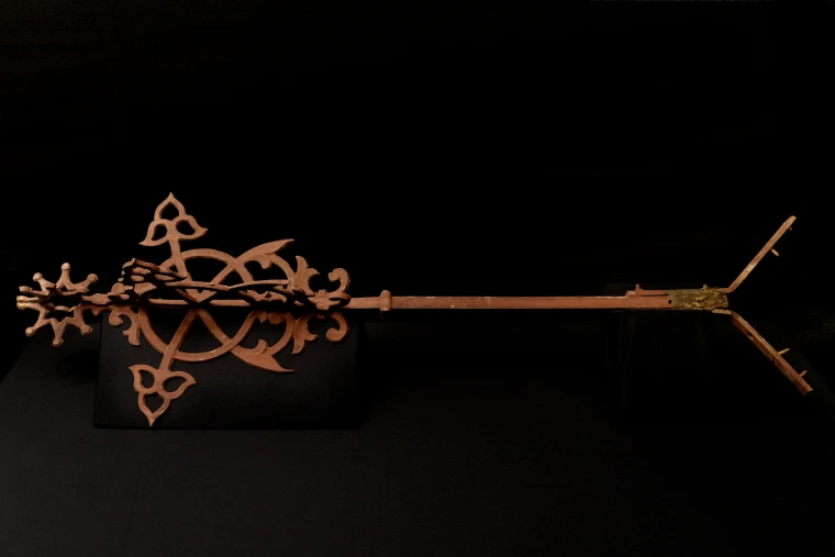 A bronze finial laying over a black backdrop. 