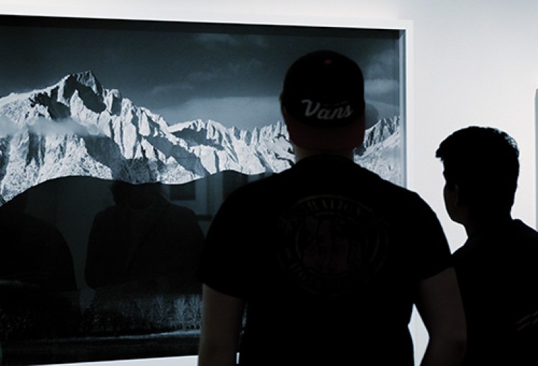 A photograph of two guests looking at a photograph of a mountain range 
