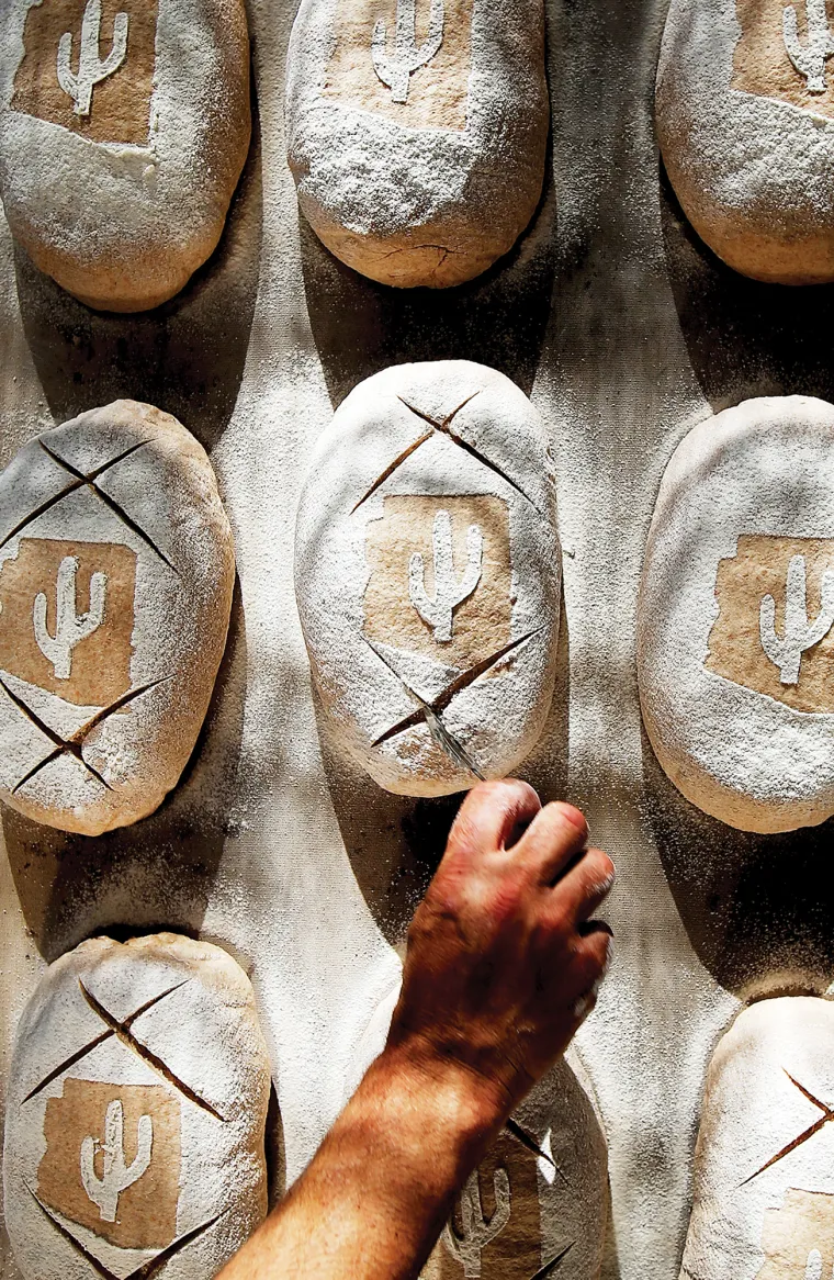 A photograph of Don carving a design into a parbaked loaf