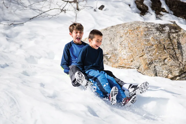 Alex and Mitchel Collins gliding down the snow in a sled