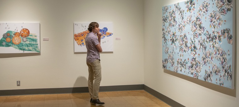 A photograph of an attendee intently staring at a large painting