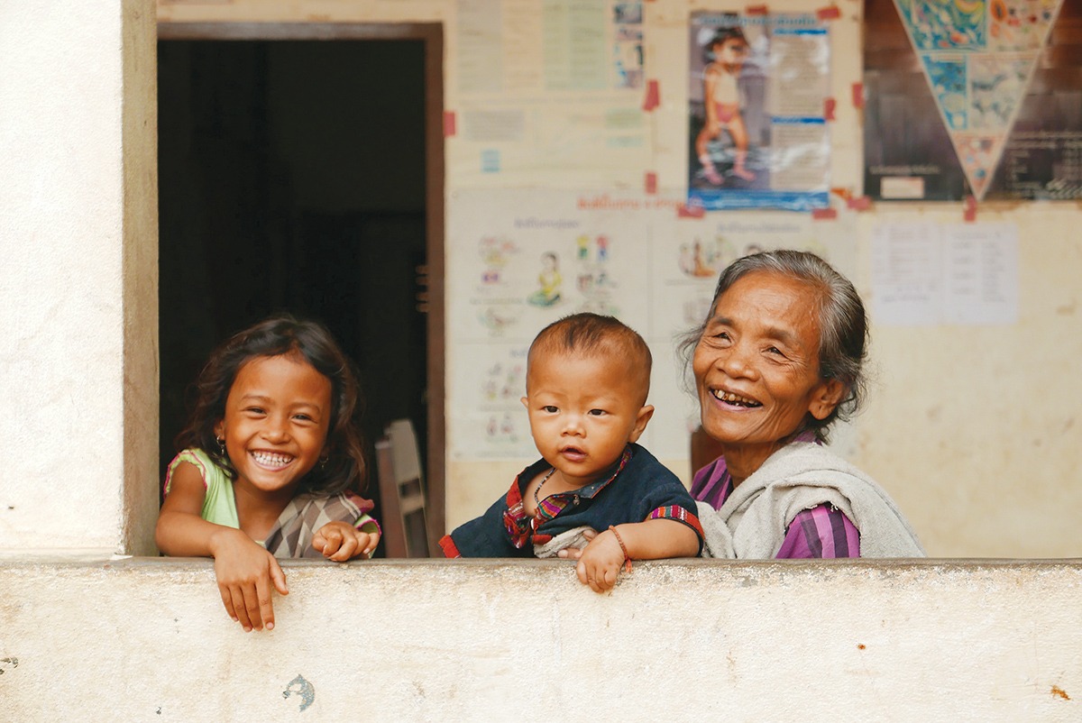 A photograph of an elderly woman lauging with two young children