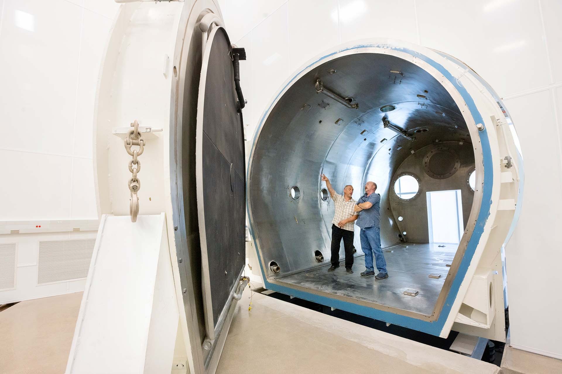 A photograph of Ruben Dominguez, a senior mechanical engineer, and Brian Duffy, a project manager in a thermal vacuum chamber