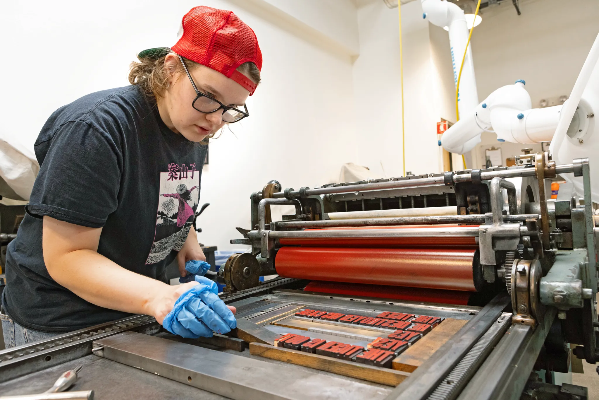 Image of Cameron Kramer using a Vandercook proving machine to work on their final project.